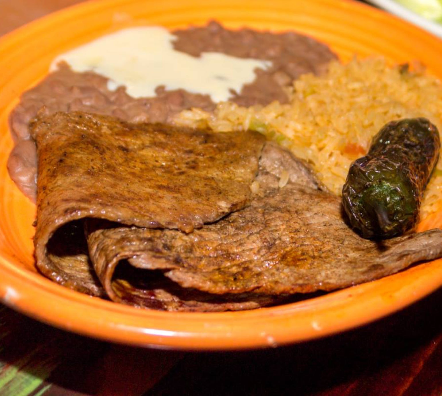 A hand holding a fresh bunch of organic carrots with vibrant green tops.